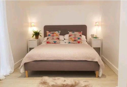 a bedroom with a bed with pillows and two tables at The Studio a super cute place nr Southwold in Southwold