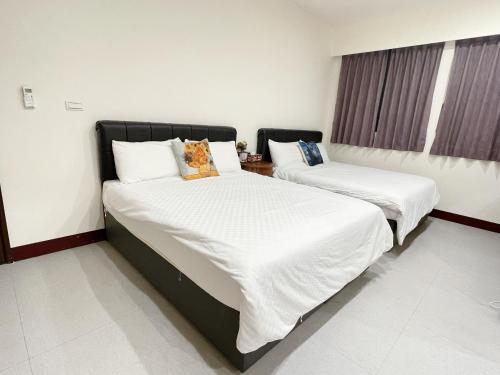 two beds in a room with white sheets at 十二籃民宿 in Magong
