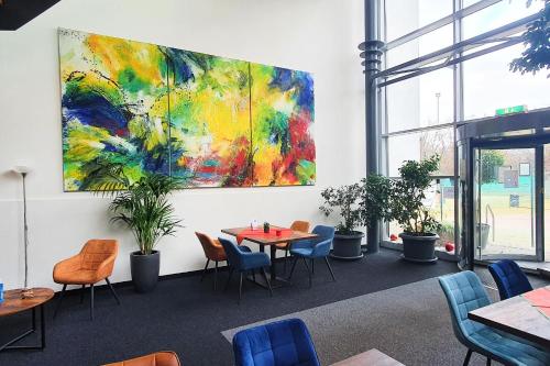 a room with tables and chairs and a painting on the wall at Sport Hotel Kenzingen in Kenzingen