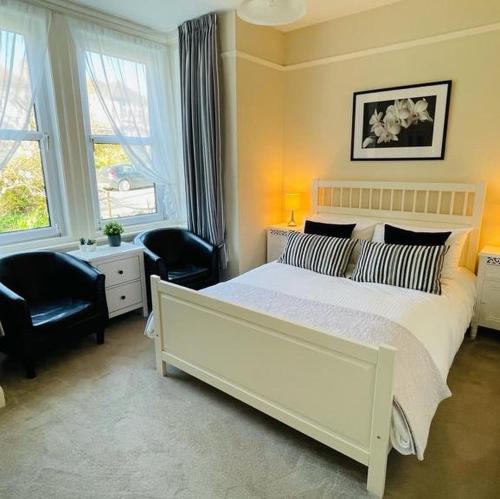 a bedroom with a large white bed and two chairs at Arbour House B&B in Swanage