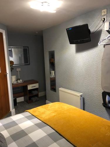 ブラックプールにあるSpringfield Hotelのベッドルーム1室(黄色いベッド1台、壁掛けテレビ付)