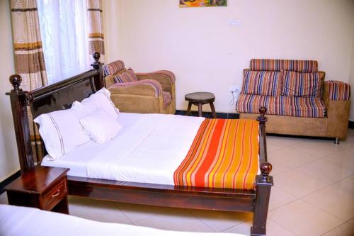 a bedroom with a bed and a couch and a chair at Acactus Hotel in Kampala