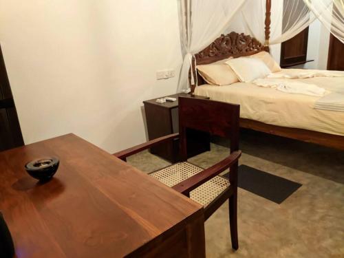 Calm House - Nature inspired private stay Mirissa في ميريسا: غرفة نوم مع طاولة وسرير وطاولة وكرسي