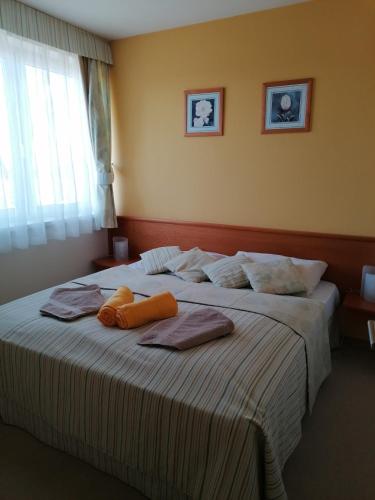 a bedroom with a large bed with towels on it at Beatrix Apartments in Bük