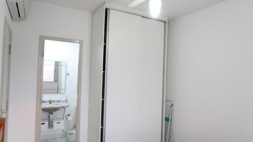 a bathroom with a glass shower door and a sink at Helbor Atlantis by Doce Lar de Bertioga in Bertioga