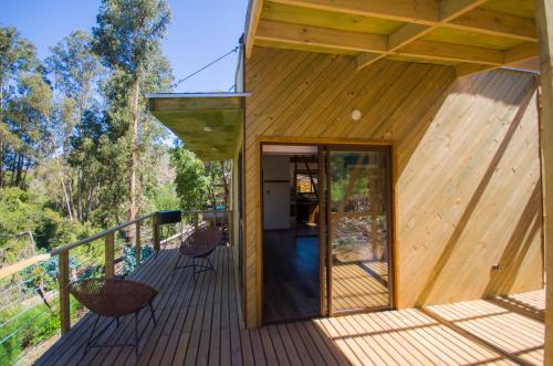 a wooden house with a glass door on a deck at cabaña con tinaja en viña narbona wines in Quillota