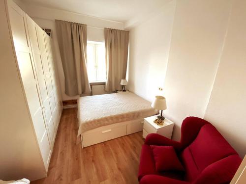 a small bedroom with a bed and a red chair at Helle 3-Zimmerwohnung in Uninähe in Braunschweig