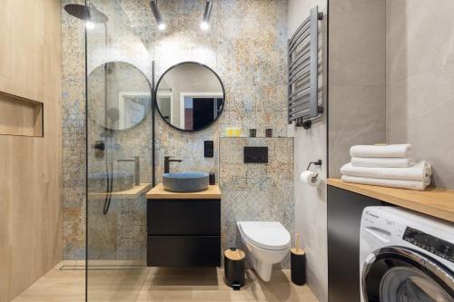 a bathroom with a sink and a toilet and a mirror at Brand New Business Apartament in Warsaw