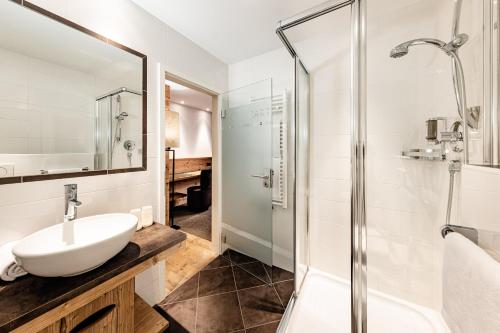 a bathroom with a sink and a shower at ArtHotel Anterleghes - Gardenahotels in Selva di Val Gardena