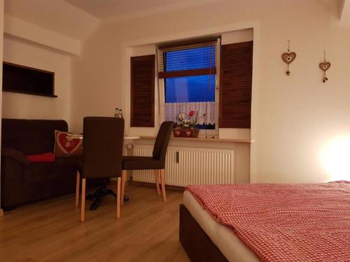 a bedroom with a bed and a desk and a window at Ferienwohnung Weber Alpenglück in Lechbruck