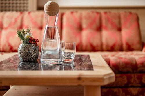 a table with two glasses and a vase on it at Romantik & Family Hotel Gardenia***S in Selva di Val Gardena