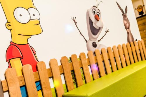 a wooden fence with a cartoon simpsons on it at Romantik & Family Hotel Gardenia***S in Selva di Val Gardena