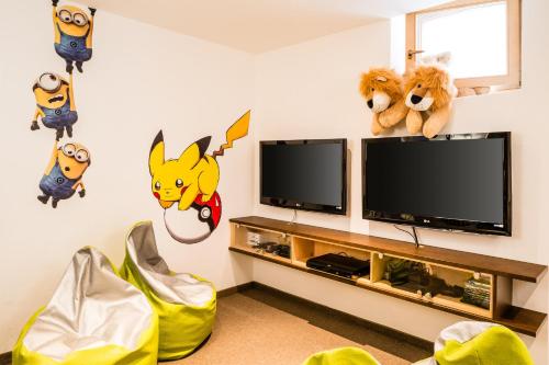 a living room with a flat screen tv and characters on the wall at Romantik & Family Hotel Gardenia***S in Selva di Val Gardena