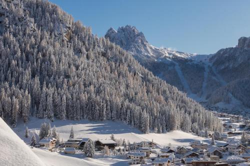a small town in the snow with a mountain at Romantik & Family Hotel Gardenia***S in Selva di Val Gardena
