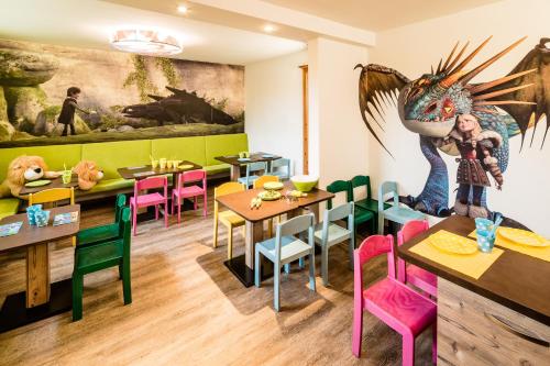 a restaurant with colorful tables and chairs and a mural at Romantik & Family Hotel Gardenia***S in Selva di Val Gardena