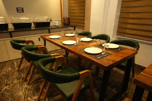 a table in a kitchen with green chairs around it at Hotel Dream Inn in Rishīkesh