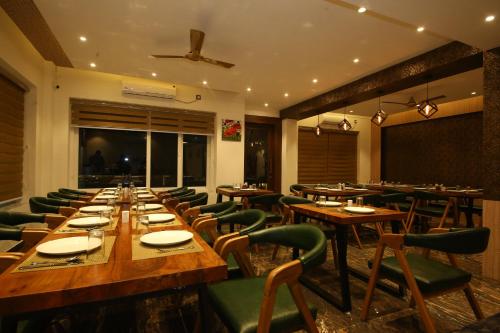 a dining room with wooden tables and green chairs at Hotel Dream Inn in Rishīkesh