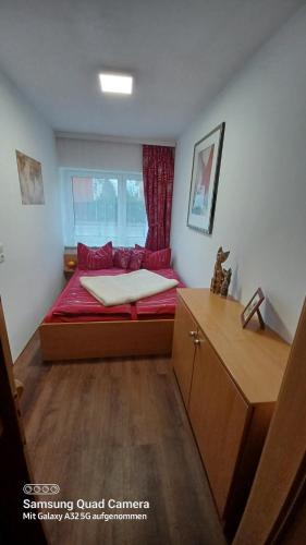 ein kleines Schlafzimmer mit einem roten Bett und einem Fenster in der Unterkunft Wohnung 3 in Ostseebad Nienhagen
