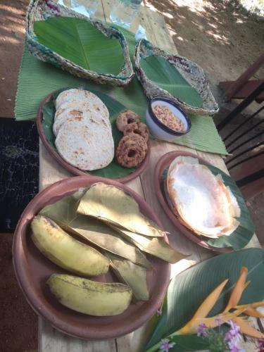 a table with plates of bread and bananas and cookies at Dambulla Tree House in Dambulla
