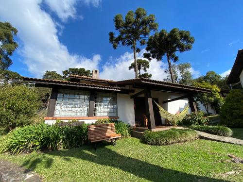 a house with a bench in the yard at Vila Suzana Parque Hotel in Canela