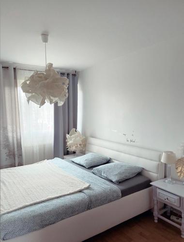 - une chambre blanche avec un lit et un lustre dans l'établissement Bel Appartement near Bâle Mulhouse Airport, à Saint-Louis