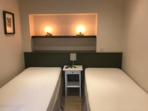 two beds in a room with a table and two lamps at Eyre Luxury Apartment in Galway