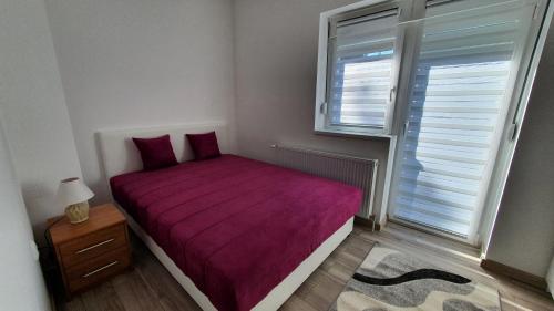 1 dormitorio con cama morada y ventana en IMPERIUM stan na dan en Inđija