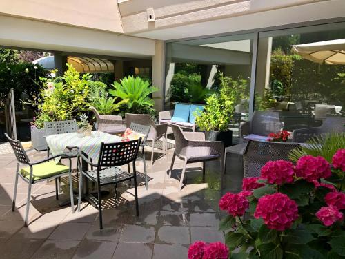 a patio with tables and chairs and pink flowers at Hotel Alfieri in Sirmione