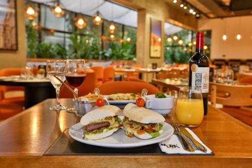 a table with two plates of sandwiches and glasses of wine at Transamerica Executive Jardins in Sao Paulo
