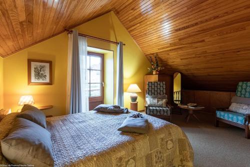 Un dormitorio con una cama grande en una habitación con techos de madera. en La Forge 