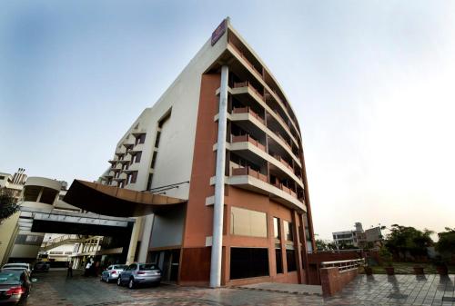 a building with cars parked in a parking lot at Clarion Bella Casa at Airport in Jaipur