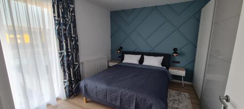 a bedroom with a bed and a blue wall at City Apartment Anton Pann in Cluj-Napoca