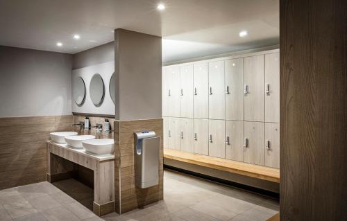 a bathroom with two sinks and white cabinets and mirrors at Fawsley Hall Hotel in Daventry