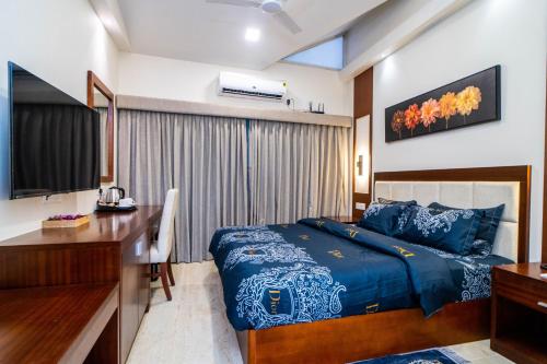 a bedroom with a bed and a desk and a television at Grande Alpine Hotel in Vagator