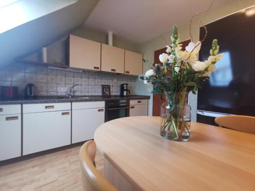 eine Küche mit einem Tisch und einer Blumenvase darauf in der Unterkunft Ferienwohnung Ammerland-Blüte in Westerstede