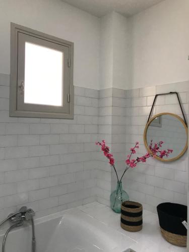 une salle de bains blanche avec un vase et des fleurs. dans l'établissement VILLA EVE, à Chateauneuf Villevieille