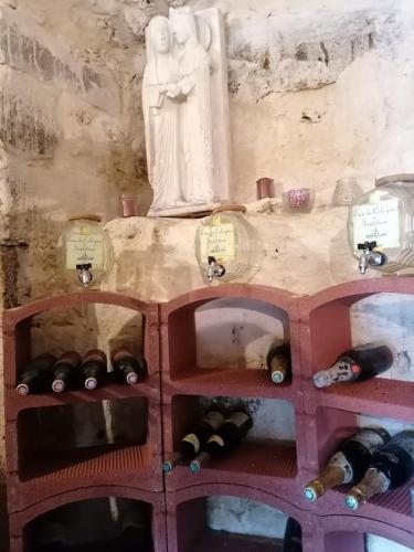 a bunch of wine bottles on a shelf with a statue at Hôtellerie Jardiniers Gourmands in Morsains