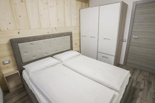 a bedroom with a white bed and a cabinet at Mountain Hut Veronza in Cavalese