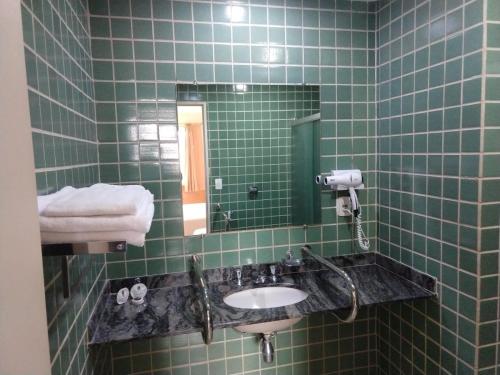 un bagno piastrellato verde con lavandino e specchio di Jaguary Hotel Sumaré a Sumaré