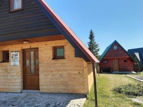 une cabane avec une porte en bois et une grange rouge dans l'établissement Bungalows Krstajić, à Žabljak