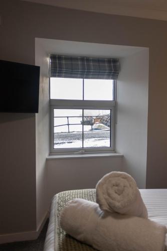 a bedroom with a bed and a window with a towel at The Rosedale Hotel & Restaurant in Portree