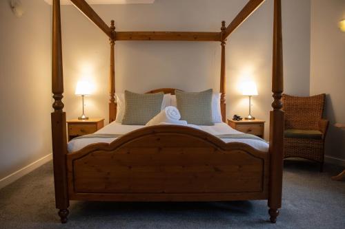 ein Schlafzimmer mit einem Himmelbett mit zwei Lampen in der Unterkunft The Rosedale Hotel & Restaurant in Portree