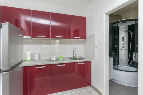 a kitchen with red cabinets and a sink at Apartments Lorenzo in Lokva Rogoznica