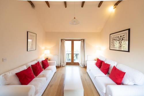 a living room with white couches and red pillows at Whitley Coach House in Whitley
