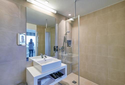 W łazience znajduje się umywalka i przeszklony prysznic. w obiekcie Rosenberger Seminar-Hotel Deutsch-Wagram w mieście Deutsch-Wagram