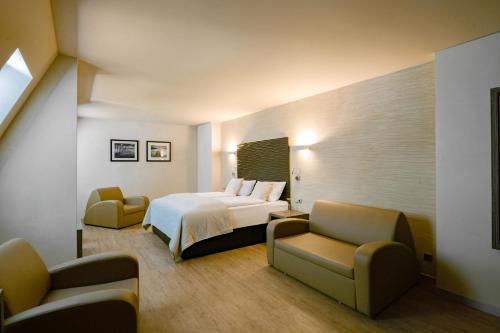 um quarto de hotel com uma cama e duas cadeiras em Artim Hotel em Berlim