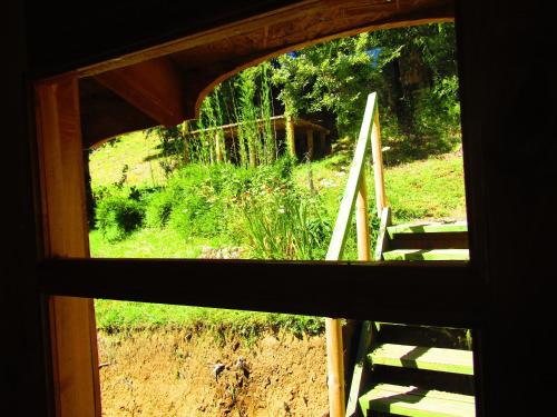 a window view of a field from a house at Refugio Montaña Kultrun Mawida, Mini-Cabaña con baño y cocina privada in Curacautín