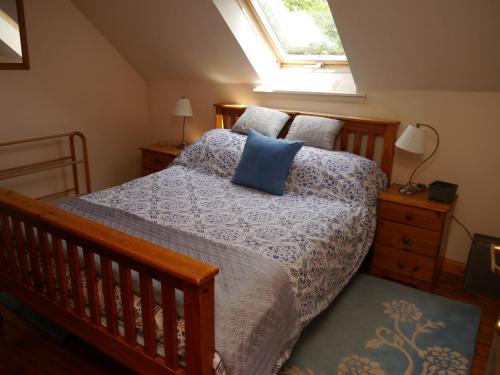 a bedroom with a bed with blue pillows and a window at Belmont Cottage in Dumfries