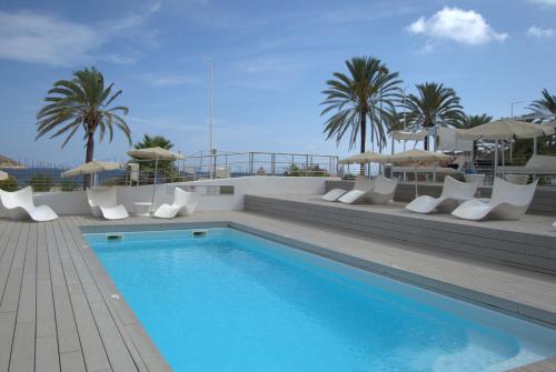 a swimming pool with chairs and umbrellas on a building at Seafront Apartment in Magaluf in Magaluf