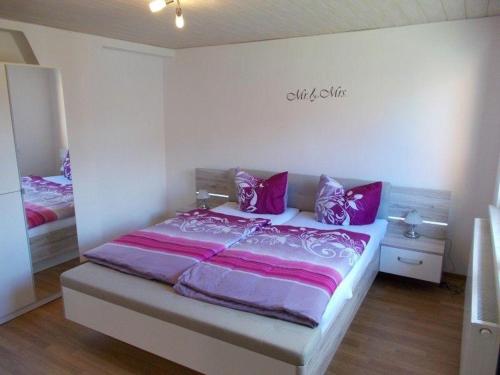 una camera con letto e lenzuola rosa e viola di Janos-Ferienwohnung a Friedrichsbrunn